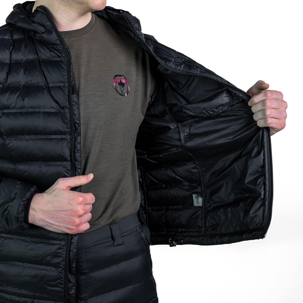 A person wearing a black hooded puffer jacket over a brown shirt, opening the jacket to show the black interior lining and zippered pocket.