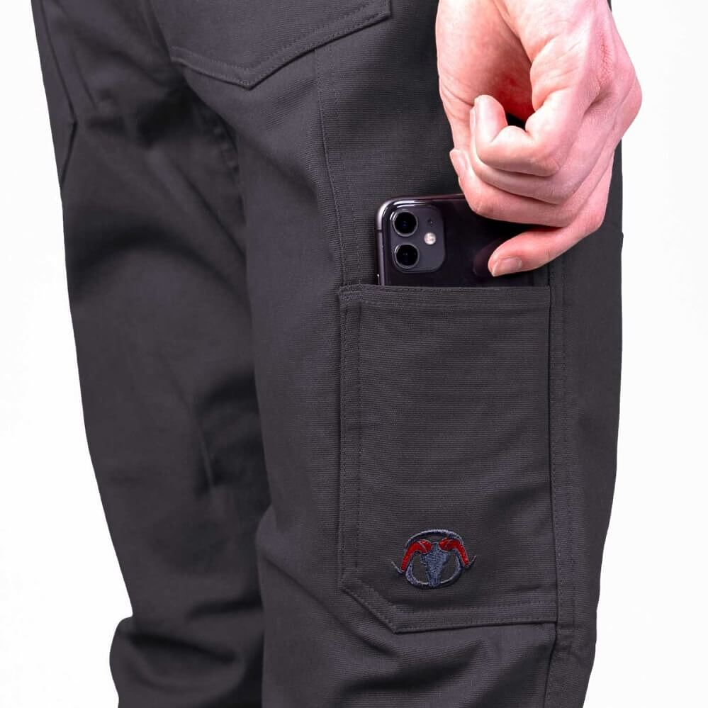 Close-up of black cargo pants with a side pocket holding a smartphone, featuring a small embroidered logo near the hem.