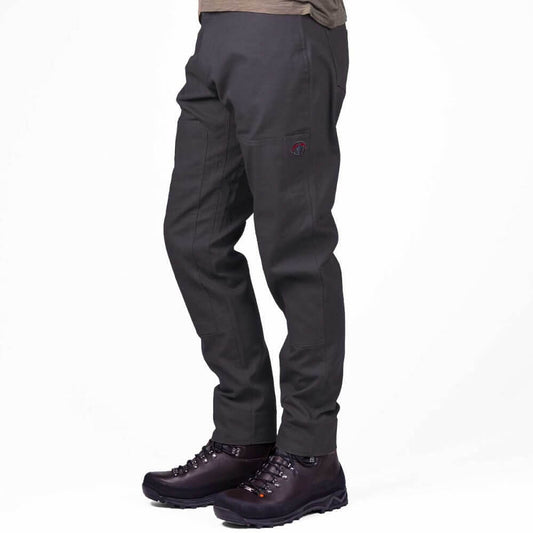 A person shown from the waist down wearing dark charcoal gray technical pants and dark brown hiking boots against a plain white studio background.