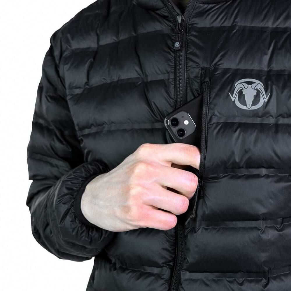 A close-up of a person wearing a black puffer jacket with horizontal quilting, a front zipper, and a gray ram head logo on the chest. The person's hand is shown pulling a black smartphone out of a zippered pocket on the jacket.