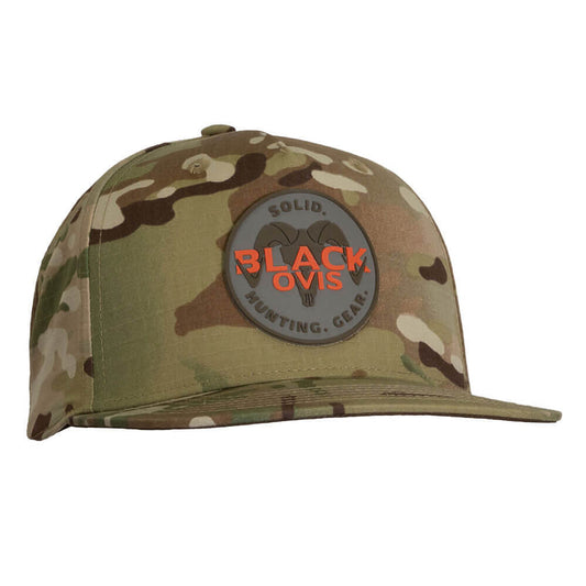 A camouflage baseball cap with a circular gray patch on the front that reads 'SOLID BLACK OVIS' in orange and black text, shown on a plain white background.