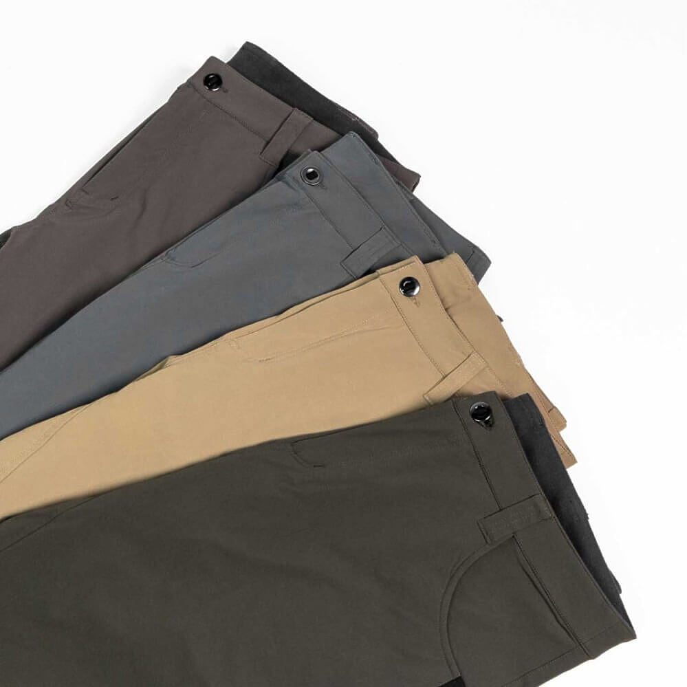Four pairs of folded chino pants in different colors (charcoal, slate blue, tan, and olive green) arranged diagonally on a white background.