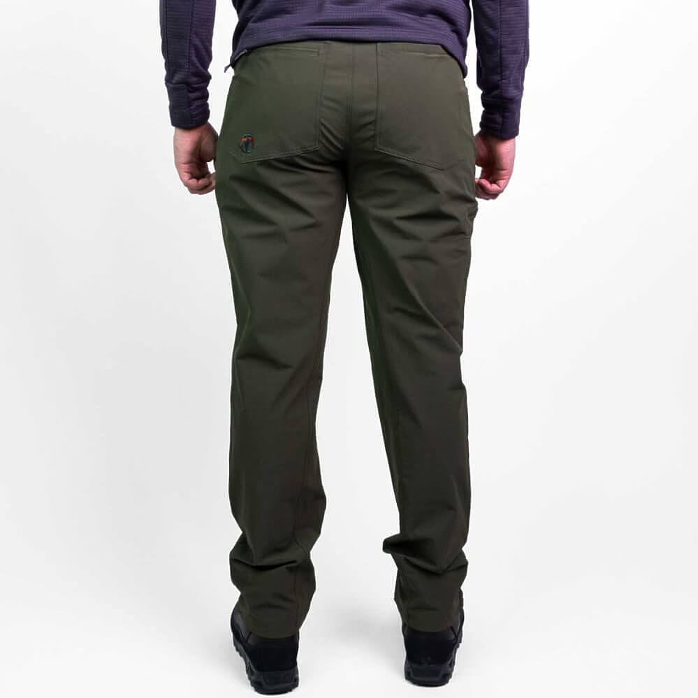A person shown from the back wearing dark olive green pants, a dark purple long-sleeve top, and black shoes against a plain white studio background.